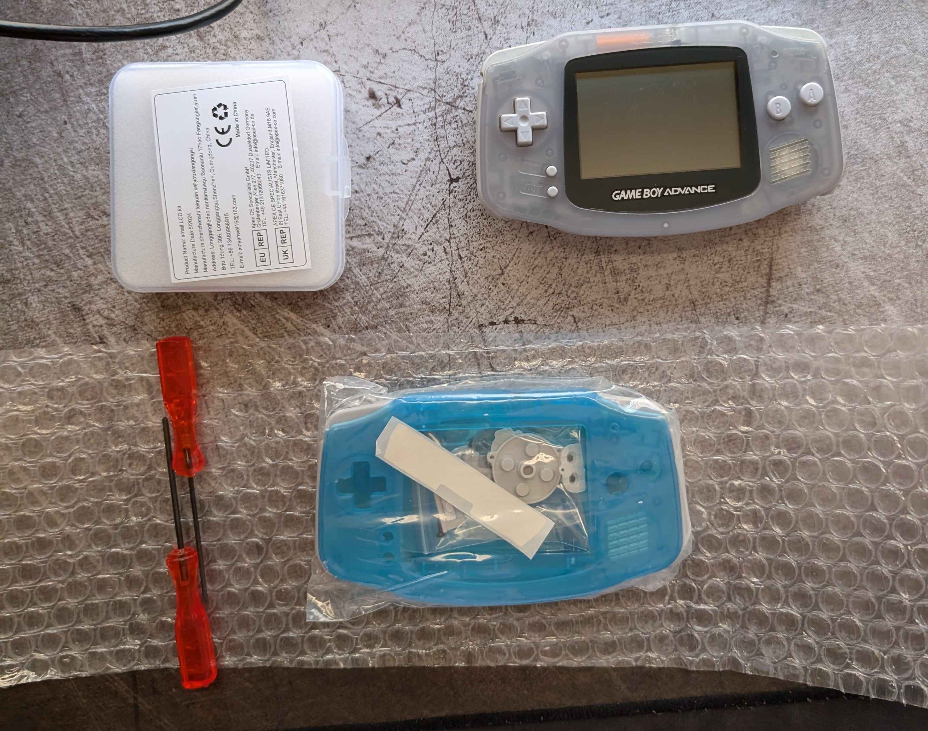 Picture of the new GBA display, the used GBA, and the new GBA shell.